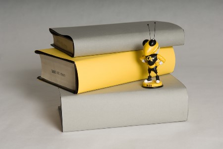 Stack of books next to Tech Yellow Jackets mascot