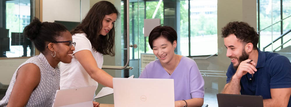 A group of students looking at a laptop and working together